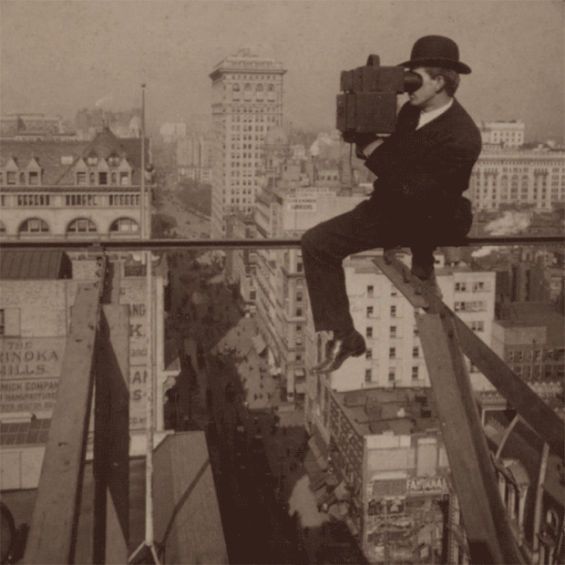 Stereoscopic image of a man sitting above the city taking a photo, late 1800s or early 1900's