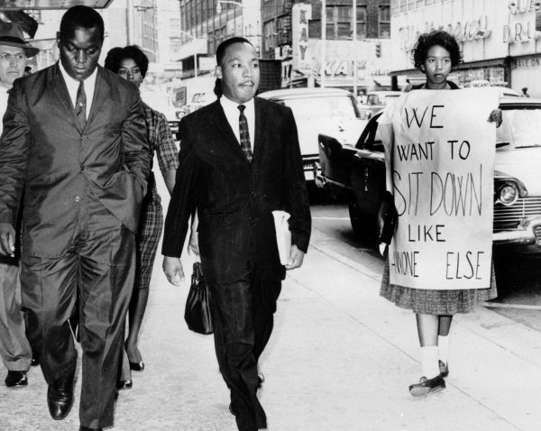 Martin Luther King Jr. under arrest by Atlanta Police Captain R.E. Little, left rear, passes through a picket line in front of a downtown department store on Oct. 9, 1960. with King is another demonstration leader, Lonnie King and an unidentified woman. King was among the 48 people arrested following demonstrations at several department and variety stores protesting lunch counter segregation. (AP Photo)