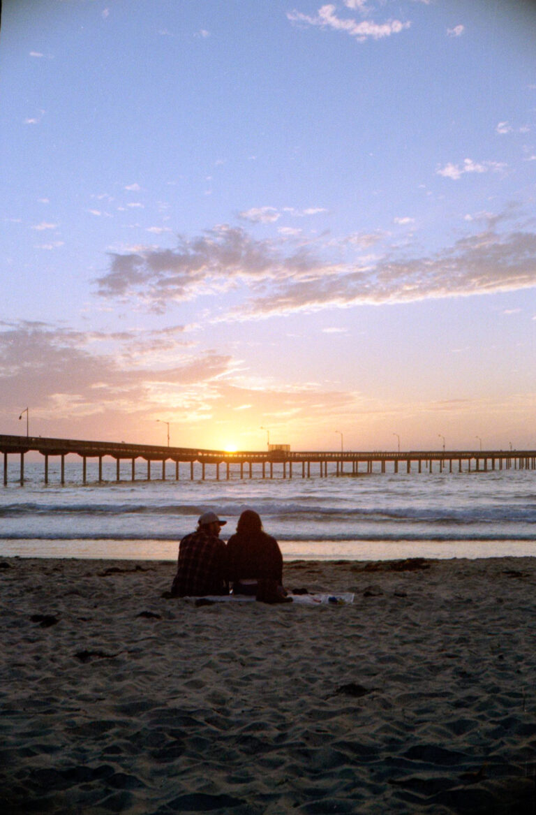 couple sitting in sand watching sunset at Ocean Beach pier San Diego, Yashica Electro 35
