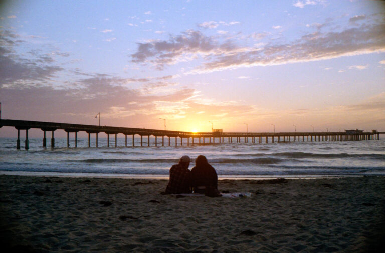 couple sitting in sand watching sunset at Ocean Beach pier San Diego, Yashica Electro 35