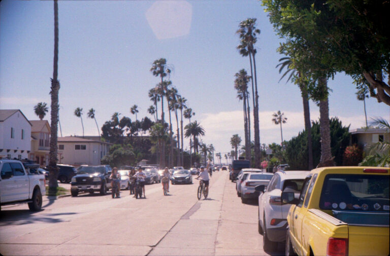 group of cyclists riding down palm lined street in Pacific Beach San Diego, Yashica Electro 35 street photography