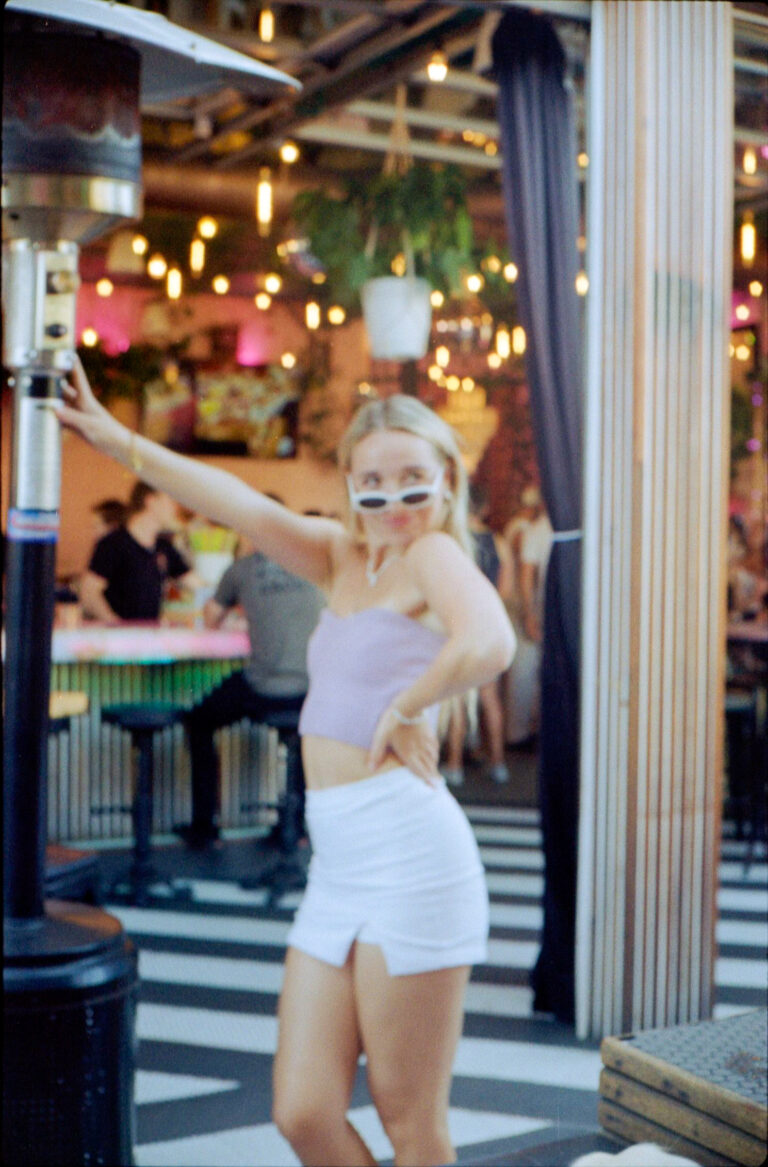 woman posing at Flamingo Deck Pacific Beach San Diego with string lights and tropical decor, Yashica Electro 35